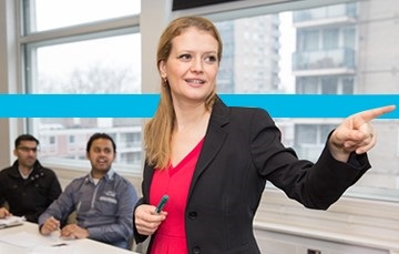 Woman in blazer speaking to apprentices